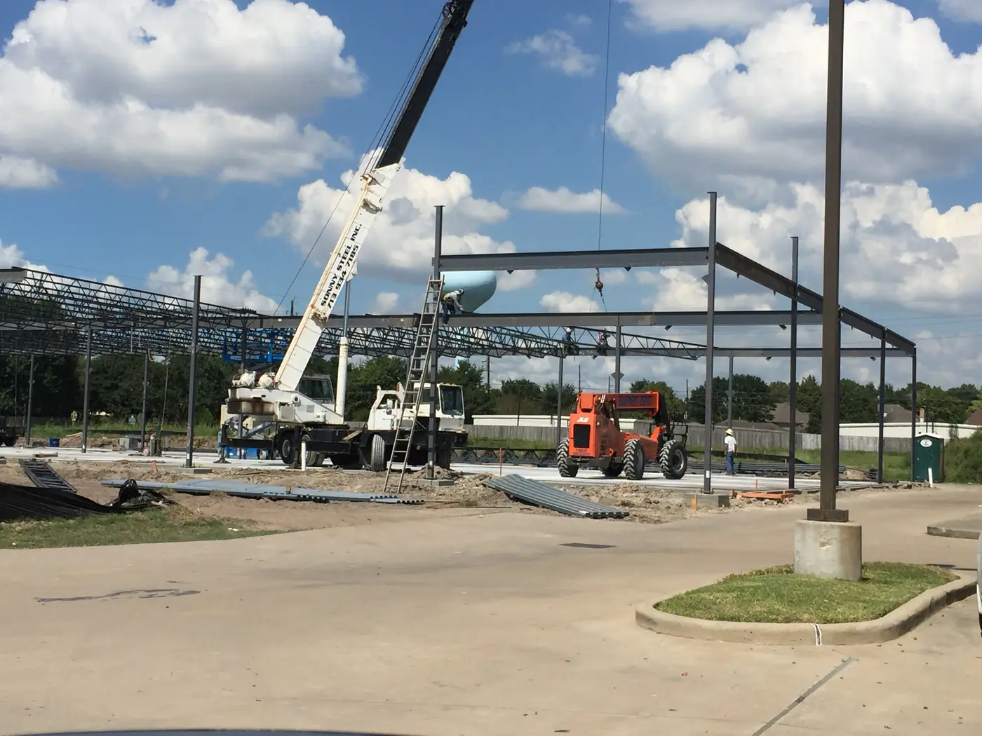 Crane setting steel beams over an active commercial site