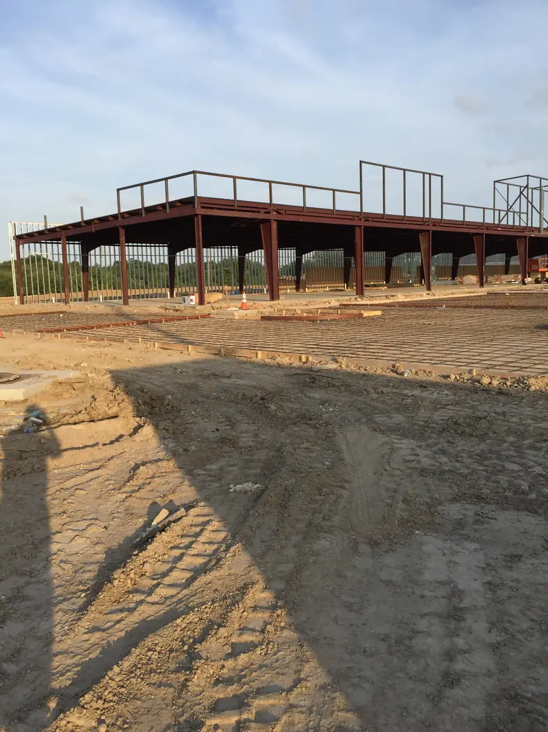 Early steel-frame erection above a graded commercial site