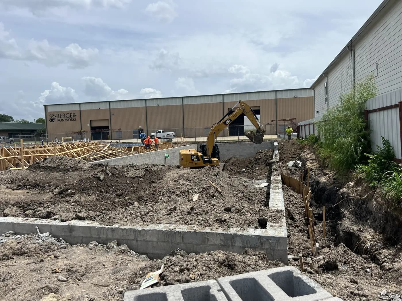 Foundation and retaining wall work progressing beside an existing building