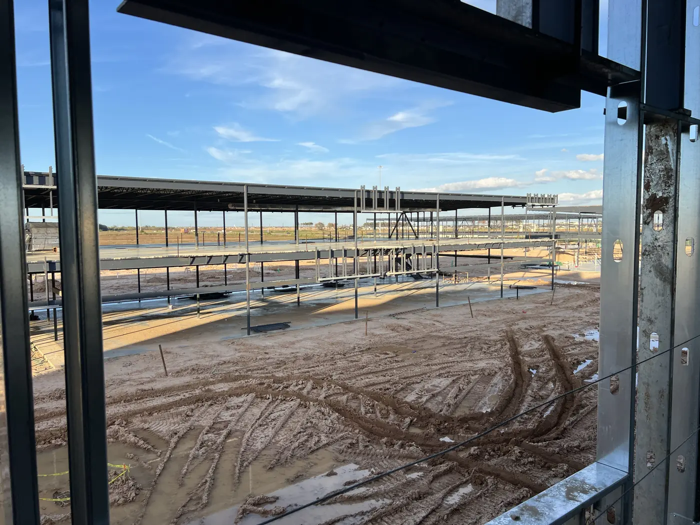 View through structural framing toward an active commercial construction site