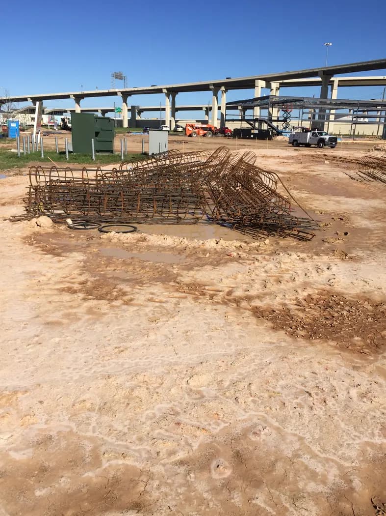 Site excavation progressing near industrial overhead framing
