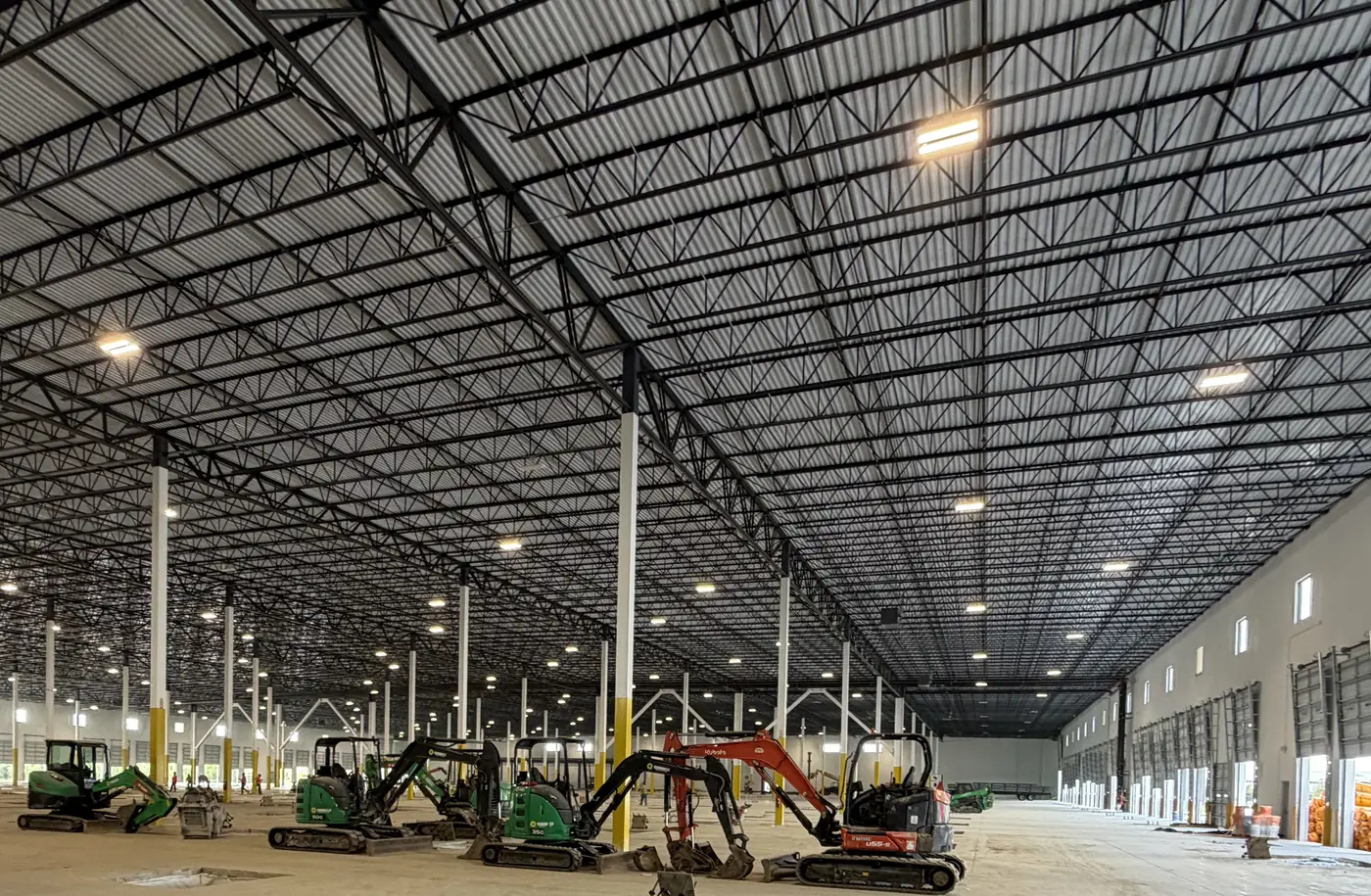 Large warehouse interior with a repeating structural roof and column grid