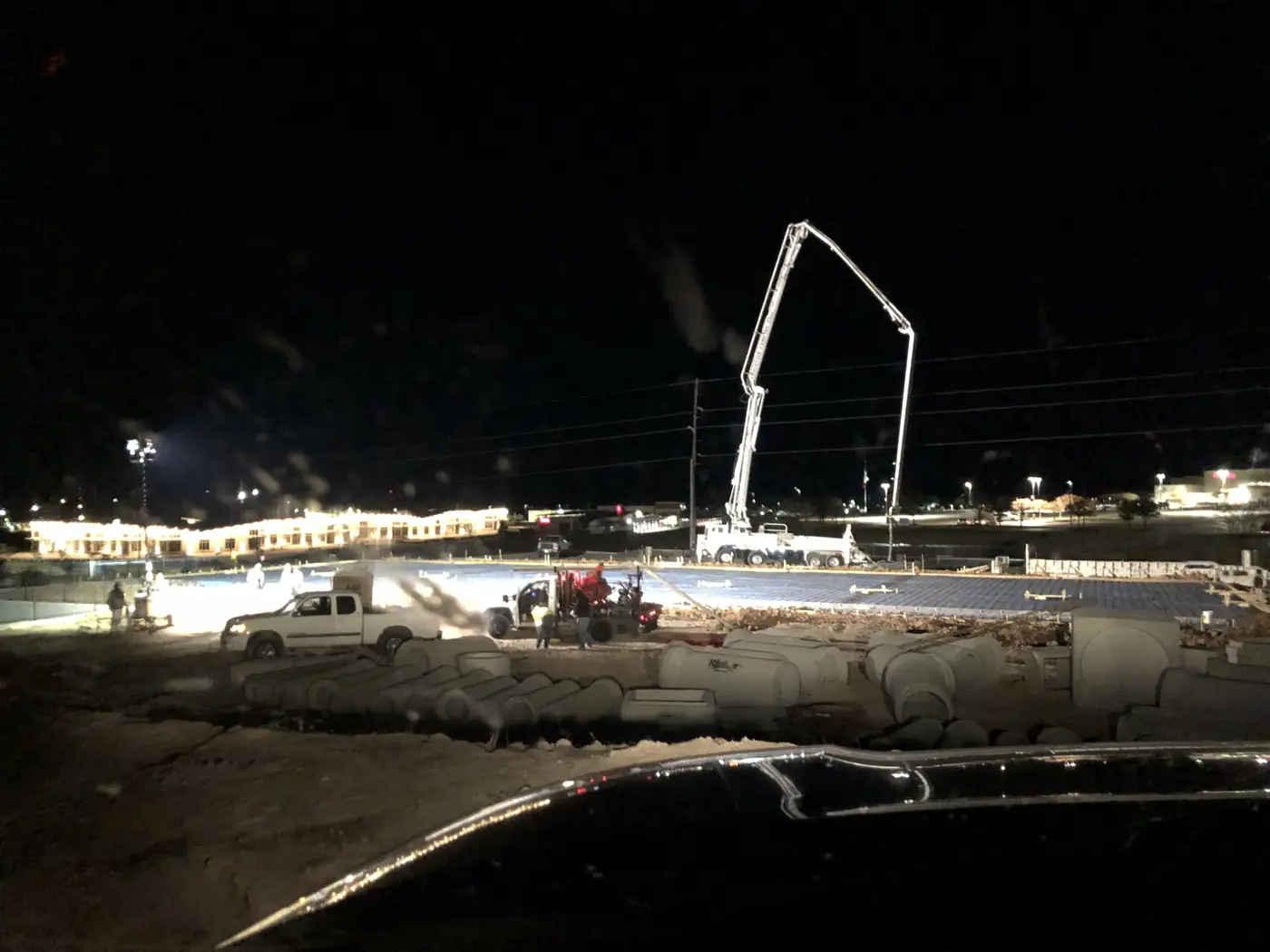 Concrete placement underway at night with a pump boom over the slab