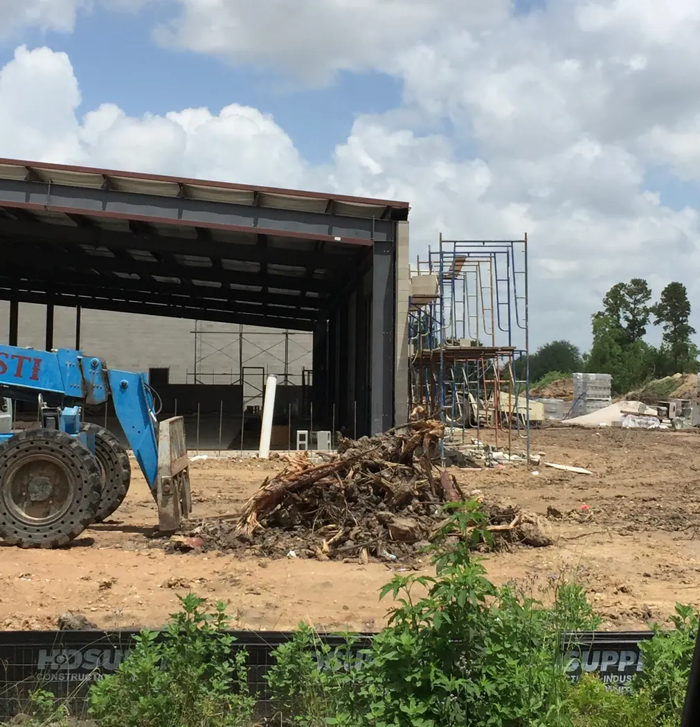 Construction materials staged within a partially enclosed steel building