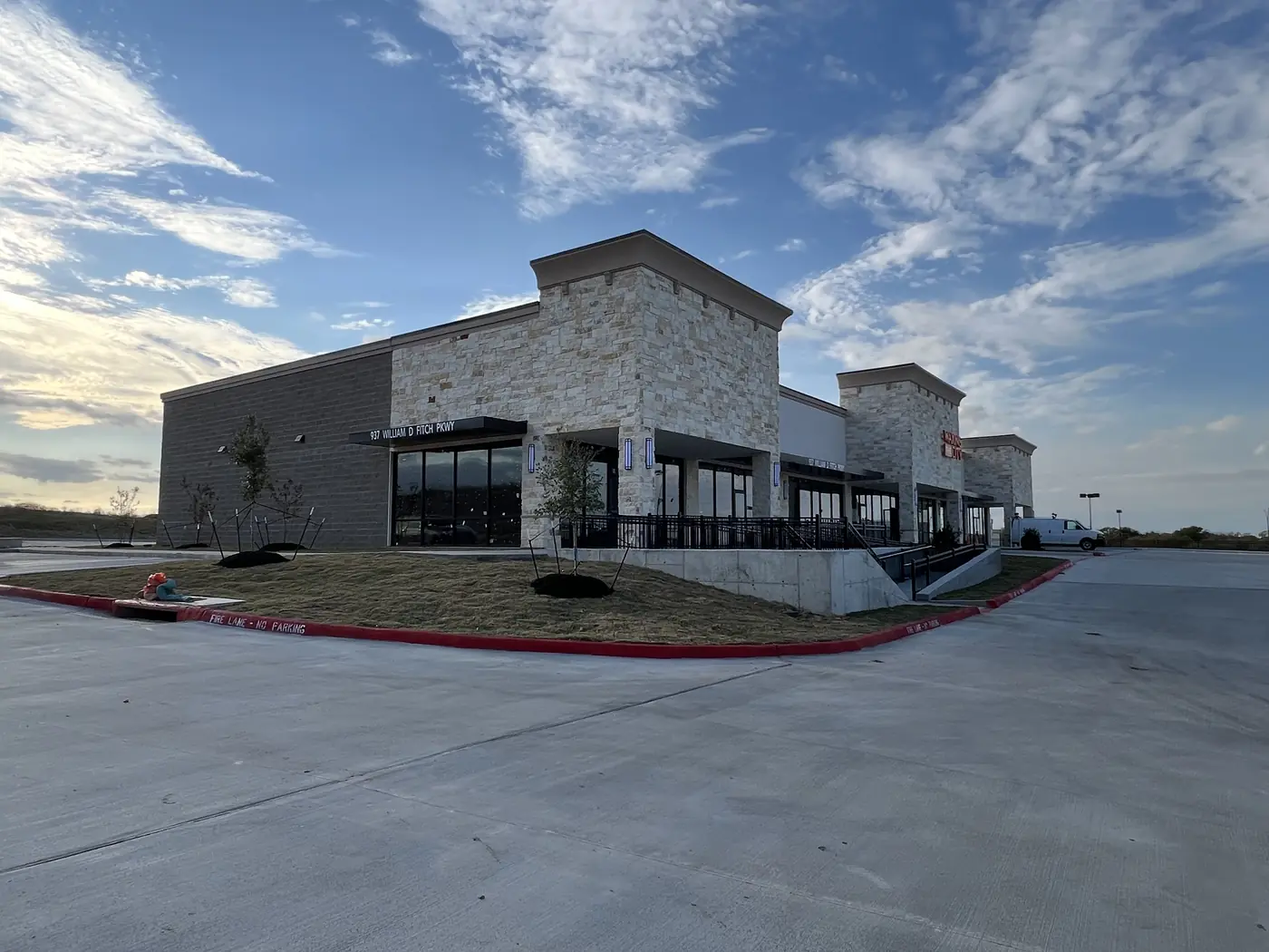 Corner view of a completed retail center with stone cladding and a covered walkway