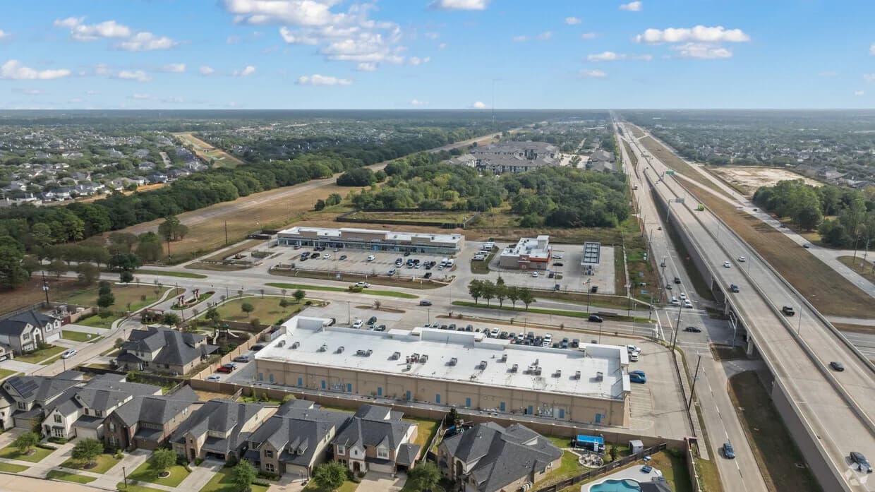 Wide aerial view of a shopping center within its roadway and neighborhood context