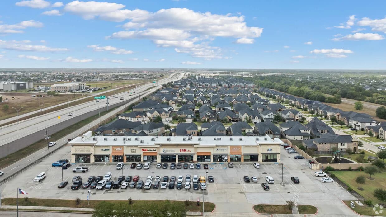 Aerial view of a completed shopping center, parking field, and surrounding development