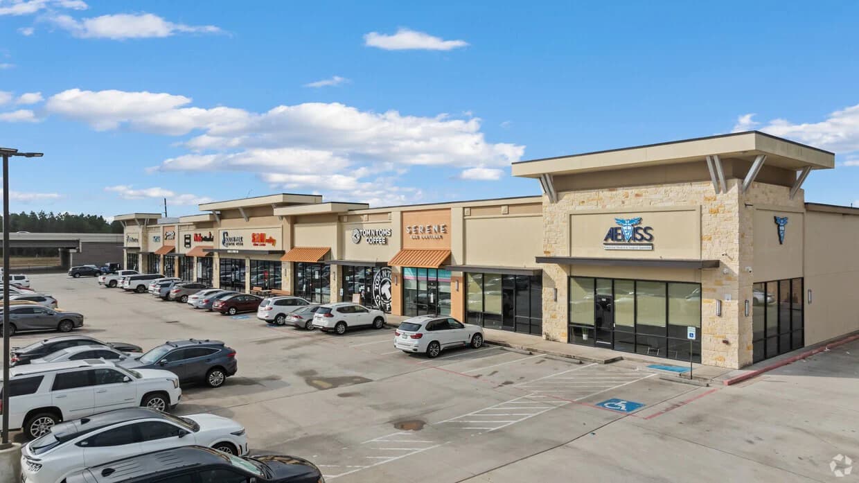 Completed multi-tenant shopping center with active storefronts and a stone-clad corner