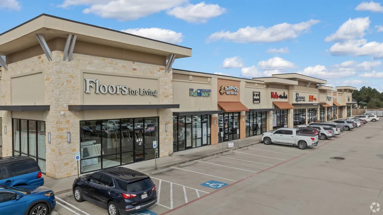 Completed shopping center storefront row with occupied tenant spaces and parking